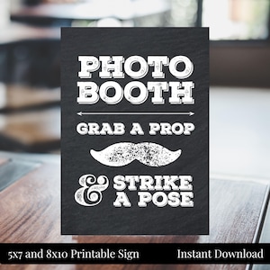 May include: Black and white printable sign that says "PHOTO BOOTH, GRAB A PROP & STRIKE A POSE". The sign features a white mustache graphic. The sign is 5x7 and 8x10 inches.