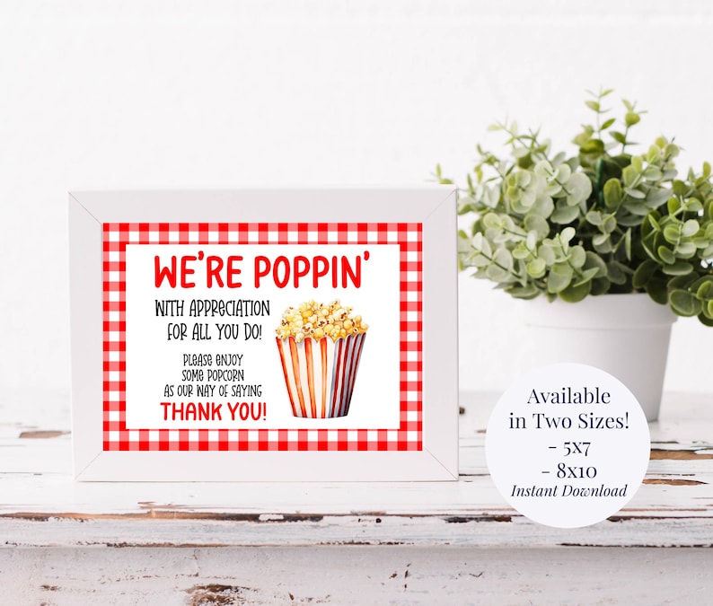 Op de afbeelding: Een ingelijste print met een rood-witte geruite rand. De tekst "WE'RE POPPIN'" staat in het rood, samen met de boodschap "WITH APPRECIATION FOR ALL YOU DO!" en "PLEASE ENJOY SOME POPCORN AS OUR WAY OF SAYING THANK YOU!". Een popcorn illustratie staat in het midden.