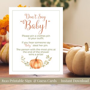 May include: A printable 8x10 sign for a baby shower with the text "Don't Say Baby!". The sign includes instructions for a game where guests pin clothes pins to their outfits and steal pins when someone says "Baby". A watercolor pumpkin illustration is featured.