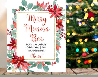 May include: A white printable sign with the text "Merry Mimosa Bar" in red script, framed by a gold border and floral accents. The sign includes instructions and the word "Cheers!" in red. A Christmas tree is in the background.