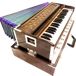 May include: A wooden harmonium with a keyboard, bellows, and a handle. The instrument has a dark brown finish with silver accents and a green and purple bellows. The keyboard has black and white keys.