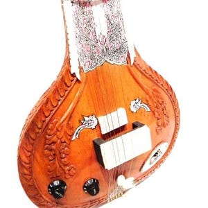 May include: A wooden sitar, a stringed instrument, with a pear-shaped body and a long neck. The instrument features intricate floral carvings and decorative inlays. The headstock has a white and pink floral design. The sitar has tuning knobs and strings.