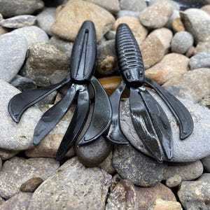 Peut inclure: Deux leurres de pêche en plastique souple noirs avec de multiples appendices. Les leurres sont conçus pour ressembler à une écrevisse.