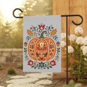 May include: A rectangular garden flag featuring a central orange pumpkin decorated with intricate folk-art style floral and leaf patterns in red, blue, and green. The design includes small acorns and oak leaves, all set against a light grey background.