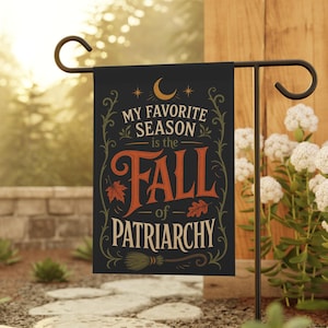 Könnte beinhalten: Eine schwarze rechteckige Gartenflagge mit einer Mondsichel und Sternen oben. Der Text MY FAVORITE SEASON is the FALL of PATRIARCHY ist in orangefarbenen und weißen Buchstaben gehalten, verziert mit orangefarbenen Ahorn- und Eichenblättern.