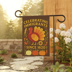May include: A brown garden flag with the text "CELEBRATING IMMIGRANTS SINCE 1620" in yellow. The flag features a turkey, wheat, sunflowers, and pumpkins. The flag is displayed on a black metal stand in a garden setting.