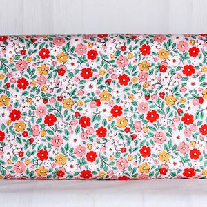 May include: A roll of fabric with a repeating floral pattern. The design features red, pink, and yellow flowers with green leaves on a white background. The fabric is tightly rolled, showcasing the detailed print.