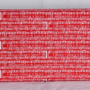 May include: Red fabric with white musical notes and lyrics. The fabric features a repeating pattern of sheet music, with the words "Christ-mas tree" visible. The overall theme is festive and musical.