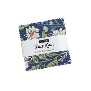 May include: A square stack of fabric squares with pinked edges, featuring a dark blue background with white floral patterns and green leaves. A white paper band wraps around the center, printed with the text Moda Fabrics True Love by Lella Boutique.