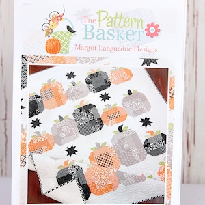 May include: A pattern packet titled "Hocus Pocus" featuring a quilt design with patchwork pumpkins in orange, gray, and black. The packet includes the text "The Pattern Basket" and "Margot Languedoc Designs."