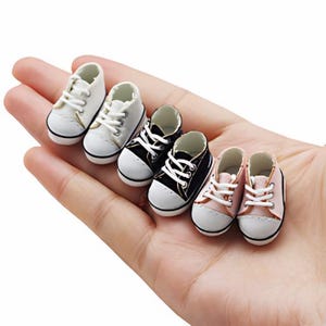 Puede incluir: Conjunto de seis zapatos en miniatura para muñecas. Los zapatos son blancos, negros y rosas. Los zapatos tienen cordones y están hechos de un material de tela.