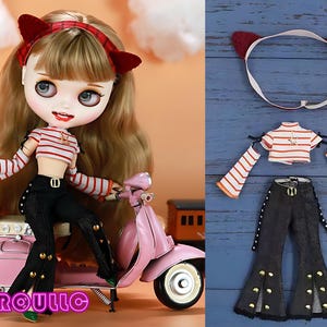 May include: A doll with long brown hair wearing a red and white striped top, black jeans, and a red headband with cat ears. The doll is sitting on a pink scooter with a brown suitcase.