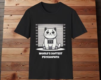 Puede incluir: Camiseta negra con un gato de dibujos animados blanco en una alineación policial. El gato tiene una etiqueta de nombre que dice "Police 35-39 93-99". El texto debajo del gato dice "World's Softest Psychopath".