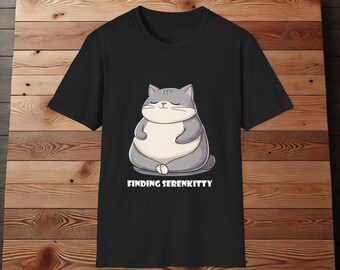 Puede incluir: Camiseta negra con una ilustración de dibujos animados de un gato gris meditando. El texto "FINDING SERENKITTY" está impreso debajo del gato.