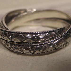 May include: A silver ring with a twisted design and intricate floral patterns.