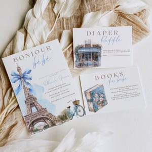 May include: A blue and white baby shower invitation with a watercolor illustration of the Eiffel Tower, a bicycle, and a book. The invitation reads "Bonjour bébé" and includes the name "Olivia Janca".