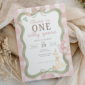 May include: A rectangular birthday invitation card featuring a pink and white checkered background with a sage green ribbon border. The text reads: Olivia is ONE silly goose, JOIN US TO CELEBRATE, SUNDAY APRIL 29 AT 11 AM, 123 Main st., Austin, TX 12345.
