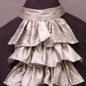 May include: A silver ruffled cravat, a type of neckwear worn by men in the 18th and 19th centuries.