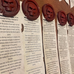 May include: Close-up of several burgundy wax seals with a skull design, affixed to aged paper scrolls. The text on the scrolls is partially visible. The seals are arranged in a row, creating a vintage aesthetic.