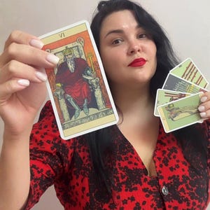 May include: A set of tarot cards featuring the Emperor card labeled VI, which depicts a bearded figure in a crown and red robes seated on a stone throne. The other cards in the set display various illustrations in muted green and grey tones.