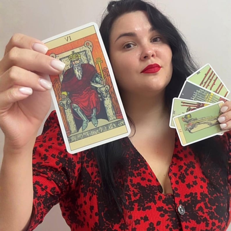 May include: A set of tarot cards featuring the Emperor card labeled VI, which depicts a bearded figure in a crown and red robes seated on a stone throne. The other cards in the set display various illustrations in muted green and grey tones.