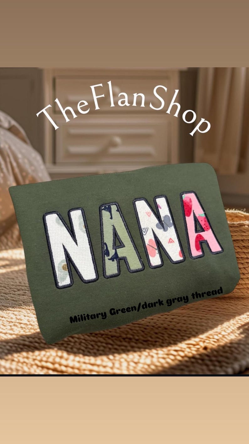 K&ouml;nnte beinhalten: Ein gr&uuml;nes Kissen mit dem Wort "NANA" bestickt in buntem, gemustertem Stoff. Der Text "Milit&auml;rgr&uuml;n/dunkelgrauer Faden" ist unter dem Wort gedruckt.