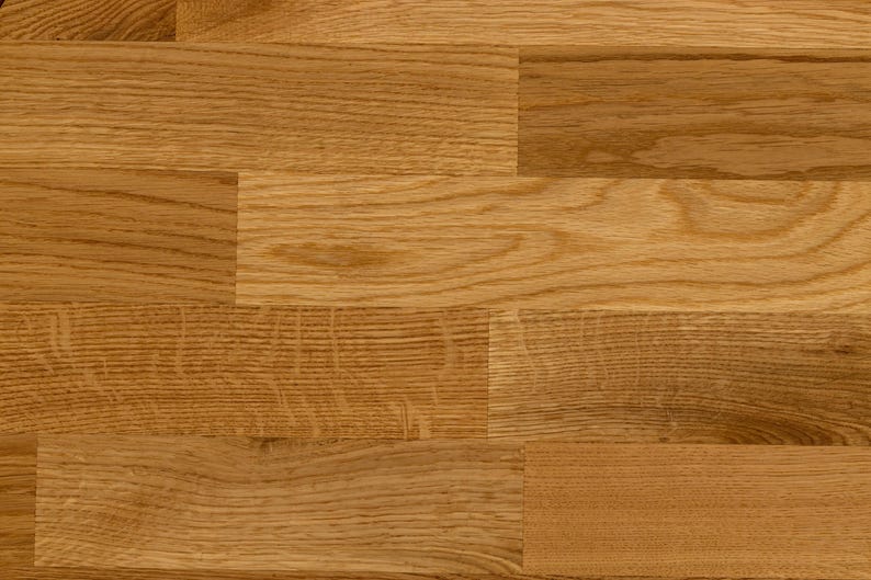 May include: A close-up of a wood floor with a natural finish. The wood planks are arranged in a staggered pattern, creating a rustic and elegant look.