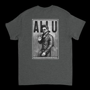 May include: Dark gray t-shirt featuring a black and white graphic of a man in sunglasses and a leather jacket. The graphic includes the name "ALLU" in large capital letters.