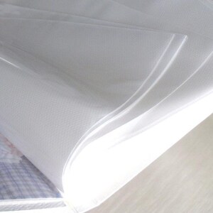 May include: A white photo album with clear plastic sleeves for holding photos. The album is open and the sleeves are visible.