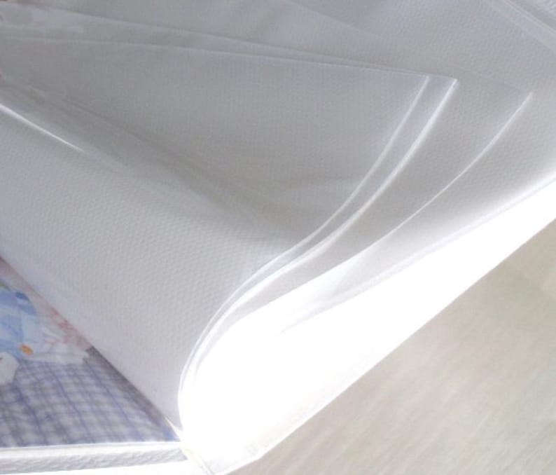 May include: A white photo album with clear plastic sleeves for holding photos. The album is open and the sleeves are visible.