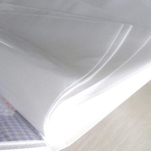 May include: Close-up of a white plastic photo album with clear plastic sleeves for holding photos. The album is open and the sleeves are visible.