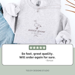 Może przedstawiać: Jasnoszara bluza z napisem "auntie goose on the loose" i ilustracją gęsi. Bluza jest połączona z niebieskimi dżinsami. Widoczna jest r&oacute;wnież recenzja klienta.