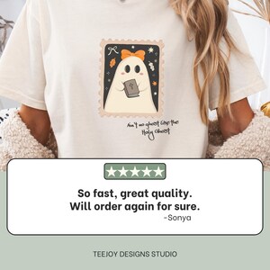 K&ouml;nnte beinhalten: Cremefarbenes T-Shirt mit einer Cartoon-Geisterillustration in einem Briefmarken-Design. Der Geist h&auml;lt ein Buch und tr&auml;gt eine Schleife. Der Text auf dem Shirt lautet "Ain't no ghost like the Holy Ghost."