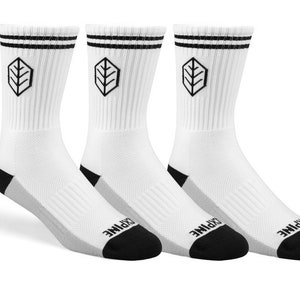 Puede incluir: Tres pares de calcetines blancos de caña alta con rayas negras y un logotipo de hoja negra. Los calcetines tienen un talón y una puntera negros y grises.