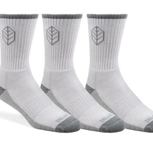 Puede incluir: Tres pares de calcetines blancos de caña alta con un logotipo de hoja gris y ribete gris. Los calcetines están hechos de un tejido suave y transpirable, perfectos para el uso diario.