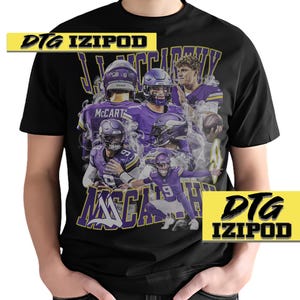 Puede incluir: Camiseta negra con un estampado gr&aacute;fico de varios jugadores de f&uacute;tbol americano que llevan uniformes morados y amarillos. El texto "DTG IZIPOD" est&aacute; impreso en la esquina superior izquierda de la camiseta y el texto "DTG IZIPOD" est&aacute; impreso en la esquina inferior derecha de la camiseta.