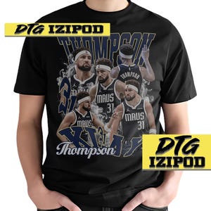 May include: Black t-shirt featuring a graphic print of a basketball player wearing a blue and white jersey with the text "Thompson" and "Maus 31" on it. The text "DTG IZIPOD" is printed on the top left corner of the shirt.