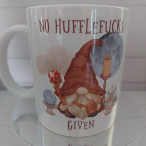 May include: White ceramic mug featuring a brown gnome illustration and the text "No Hufflepuffs Given".