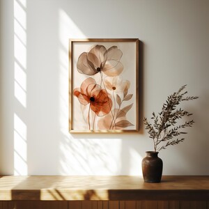 K&ouml;nnte beinhalten: Ein gerahmter Kunstdruck mit Aquarellblumen in Braun-, Rost- und Cremet&ouml;nen. Das Kunstwerk wird in einem Holzrahmen pr&auml;sentiert und h&auml;ngt an einer wei&szlig;en Wand. Eine Vase mit getrocknetem Laub steht auf einer Holzoberfl&auml;che.