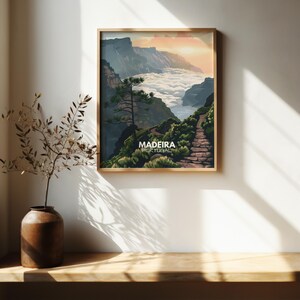 May include: A vintage travel poster with a scenic view of a mountain path leading to a valley with clouds. The poster is framed in wood and has the text "MADEIRA PORTUGAL" at the bottom.