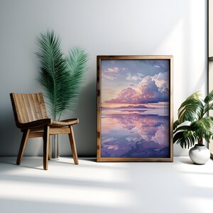 May include: A framed print of a landscape with a large, fluffy cloud reflecting in a still body of water. The sky is a soft pink and purple, and the water is a light blue. The frame is a dark brown wood.