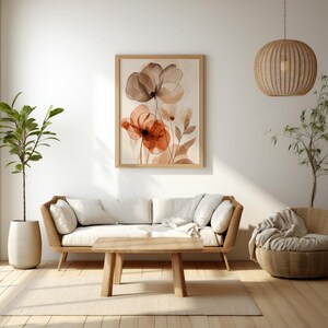 K&ouml;nnte beinhalten: Gerahmter Kunstdruck mit Aquarellblumen in Braun-, Orange- und Wei&szlig;t&ouml;nen. Das Kunstwerk h&auml;ngt &uuml;ber einem hellen Sofa und einem Holztisch und schafft eine warme Wohnraumszene. Die Szene zeigt auch eine H&auml;ngeleuchte.