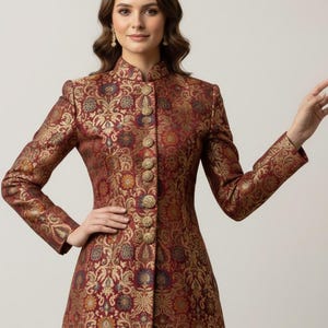 May include: A long, burgundy brocade coat with a high collar and gold buttons. The coat features an intricate floral pattern in gold, blue, and orange. The sleeves are long, and the coat is buttoned up the front.
