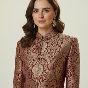 May include: A long-sleeved jacket featuring a high mandarin collar and a front closure. The garment is crafted from a deep burgundy fabric adorned with an intricate, repeating gold floral brocade pattern throughout the entire surface.