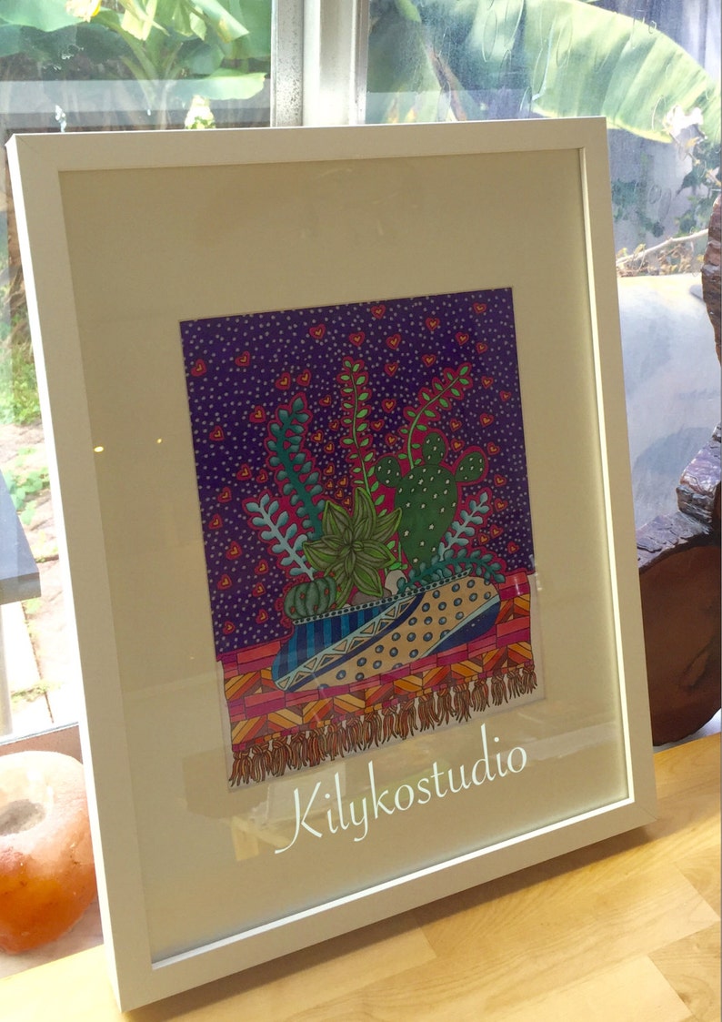 May include: A framed illustration of a colorful potted plant with a cactus, succulents, and other greenery. The background is a purple and pink patterned design with white dots. The artist's signature "Kilykostudio" is in the bottom right corner.