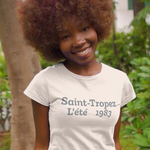 May include: White t-shirt with the text "Saint-Tropez L'été 1983" printed in gray on the front.