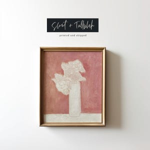 May include: A framed painting of a white flower arrangement in a vase against a pink background. The painting is titled "Scout + Tallulah" and has the text "printed and shipped" below the title.