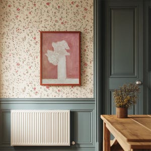May include: A white radiator with a white trim around it, a framed painting of white flowers in a vase on a pink background, a wooden table with a vase of dried flowers on it, and a green door with a white door knob.