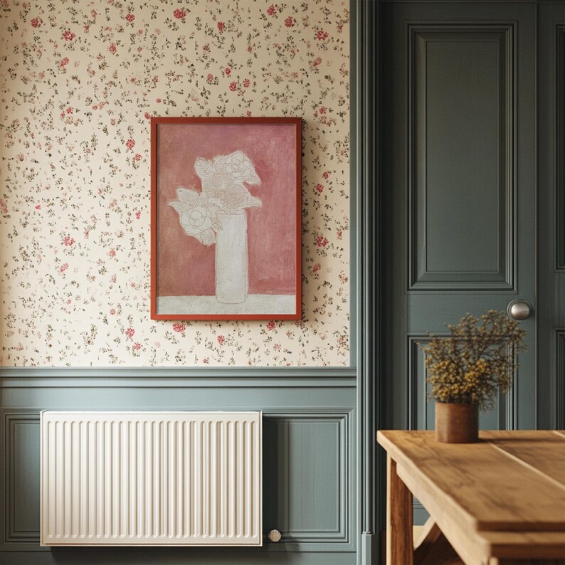 May include: A white radiator with a white trim around it, a framed painting of white flowers in a vase on a pink background, a wooden table with a vase of dried flowers on it, and a green door with a white door knob.