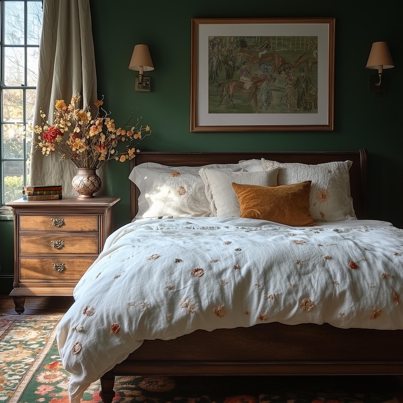 May include: A bedroom scene featuring a wooden bed with a white comforter and pillows. The comforter is adorned with floral embroidery. An orange velvet pillow adds a pop of color. A wooden nightstand with a vase of flowers and a framed artwork complete the cozy setting.